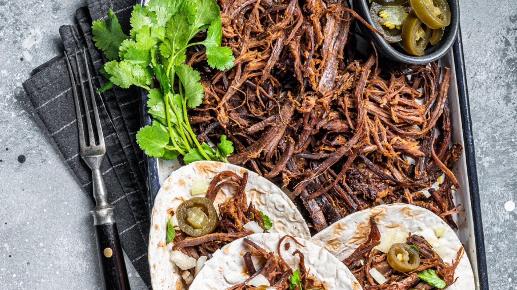 Shredded barbacoa beef with tortillas, cilantro and jalapeños